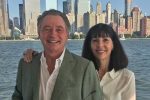 A man and woman smile in front of NYC